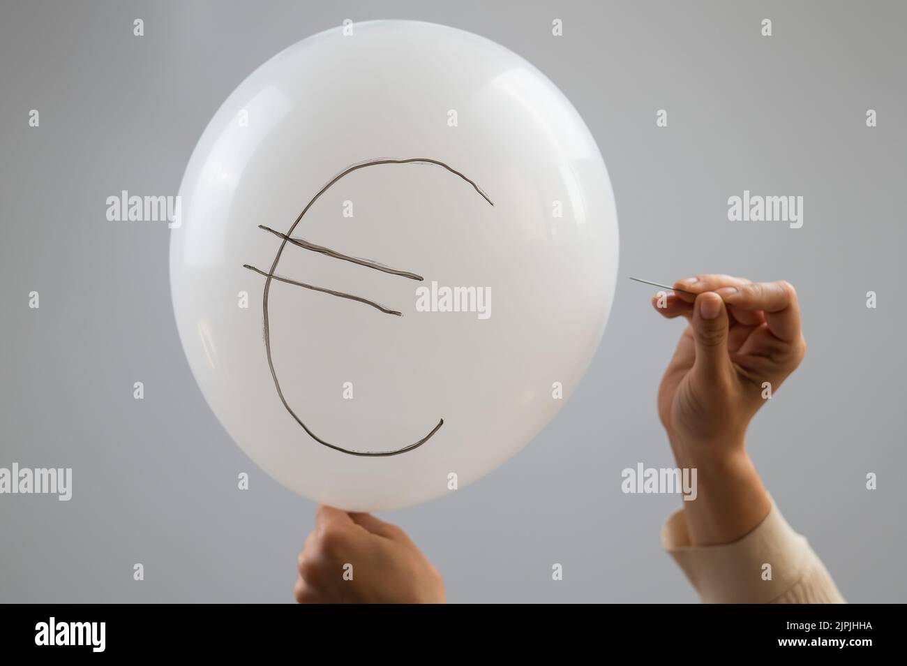 Une femme éclate avec une aiguille un ballon avec l'inscription euro. Banque D'Images