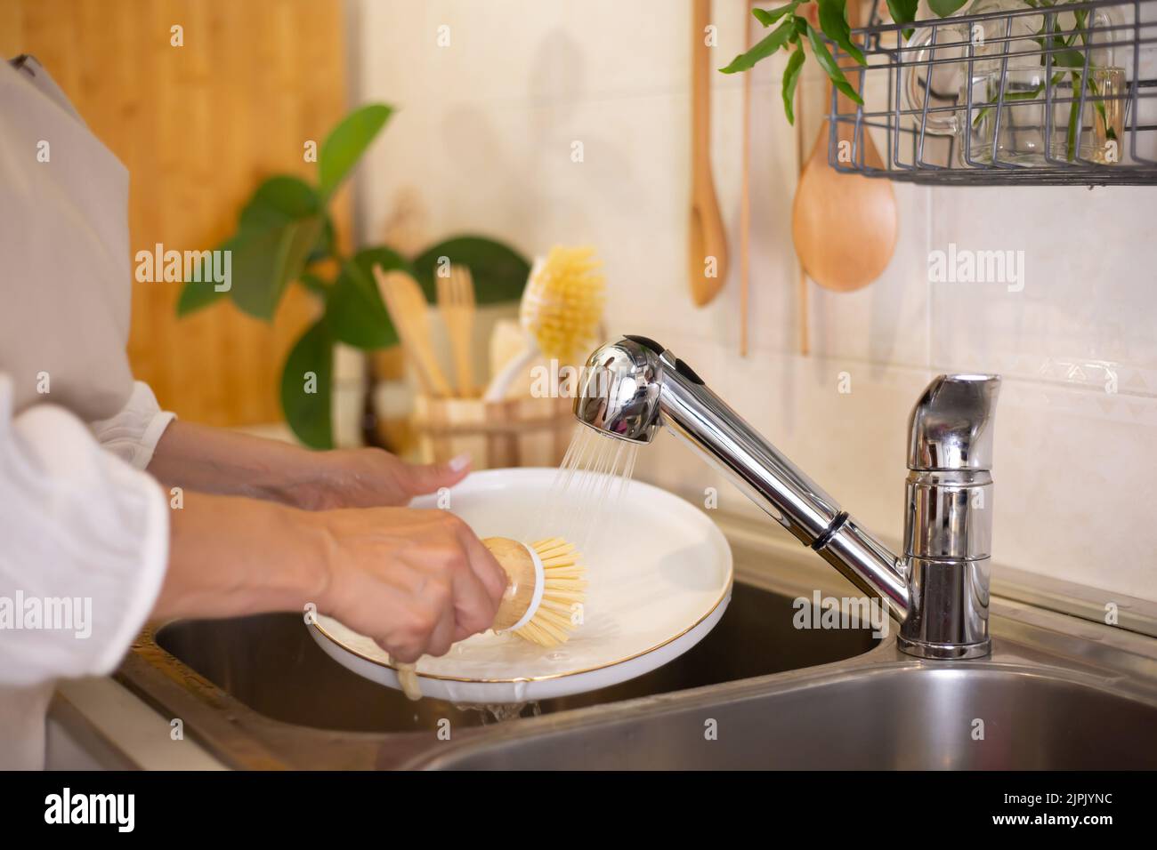 Concept zéro déchet. Accessoires de cuisine écologiques. Brosses, savon naturel, Une femme lave la vaisselle avec des produits naturels et une brosse. ECO sans déchets Banque D'Images