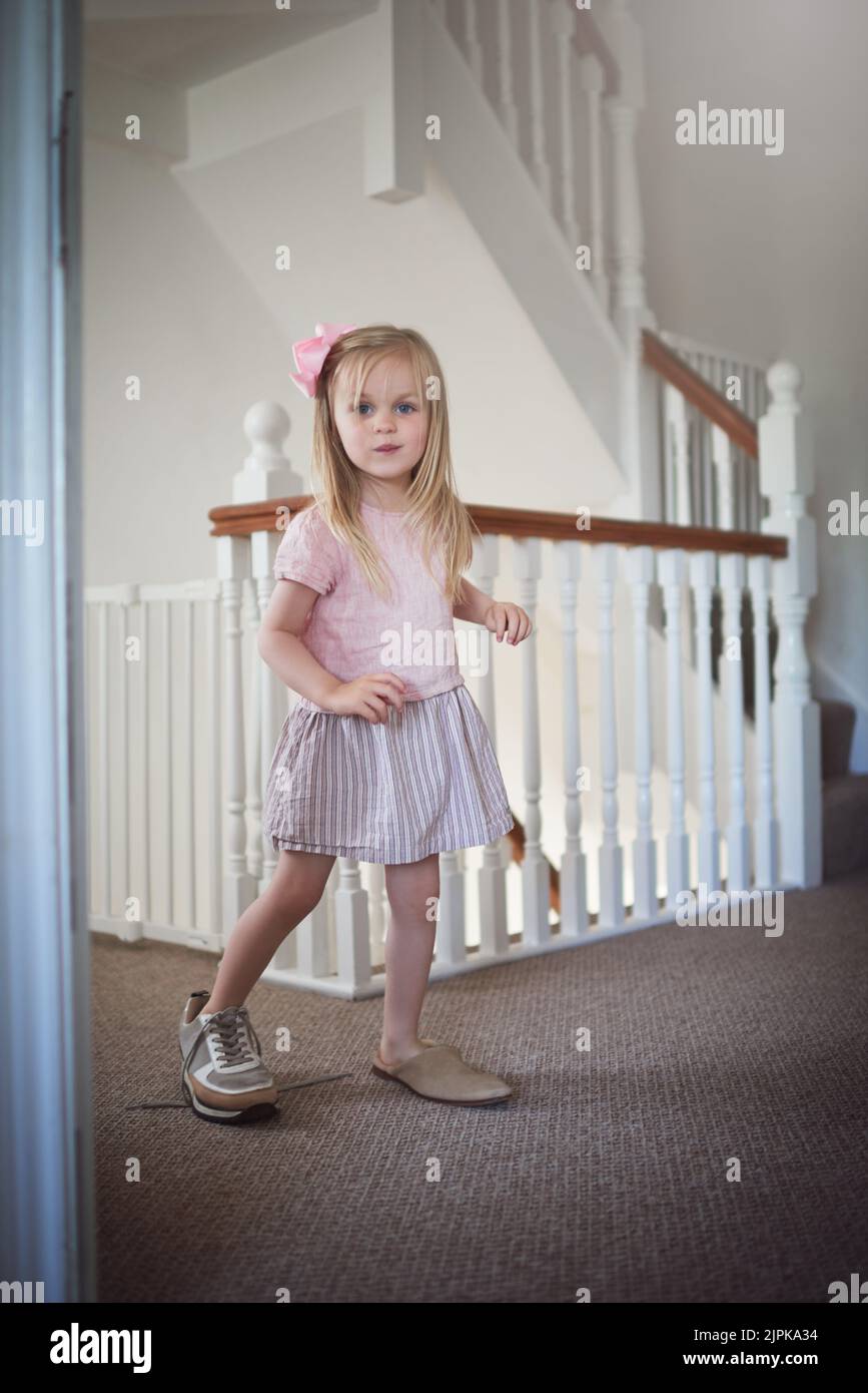 Apprendre à se mettre dans quelqu'un Elses chaussures. Une adorable petite fille marchant autour de la maison dans des chaussures adultes. Banque D'Images