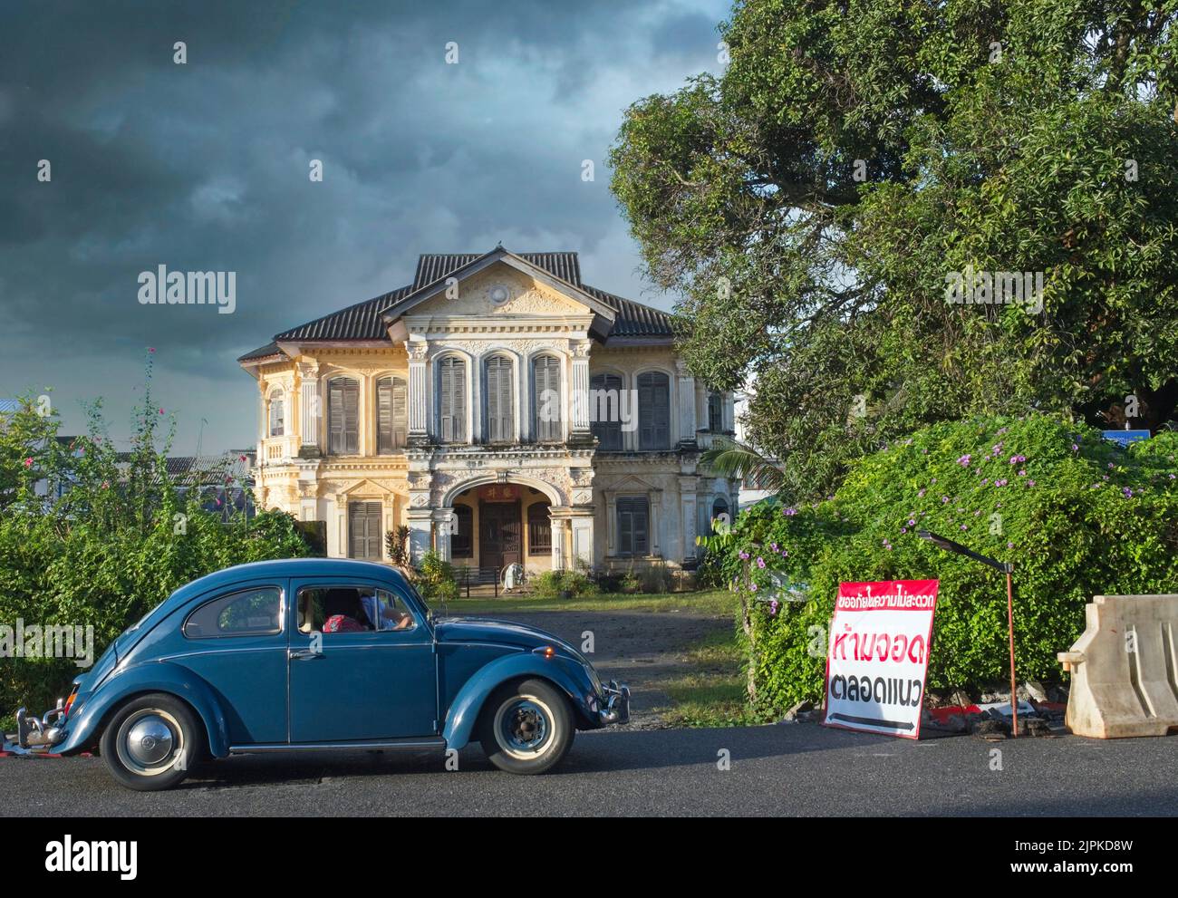 Un VW Beetle s'arrête à Luang Amnart Nararak Mansion, une ancienne villa de marchands dans la vieille ville de Phuket, Thaïlande, des nuages sombres de mousson qui se profilent Banque D'Images