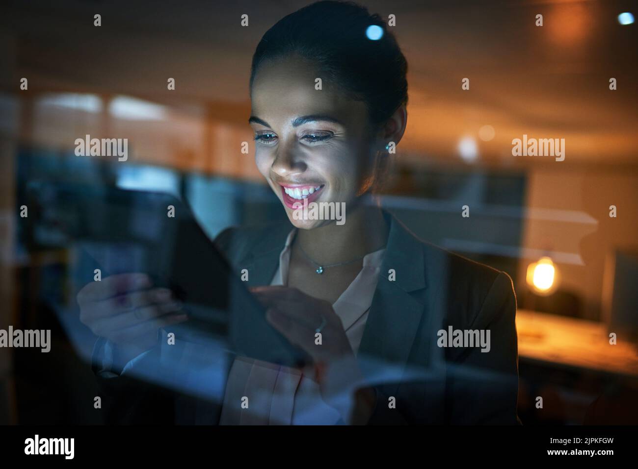 Elle se montre dévouée à son travail en tout temps. Une jeune femme d'affaires utilisant une tablette dans le bureau la nuit. Banque D'Images