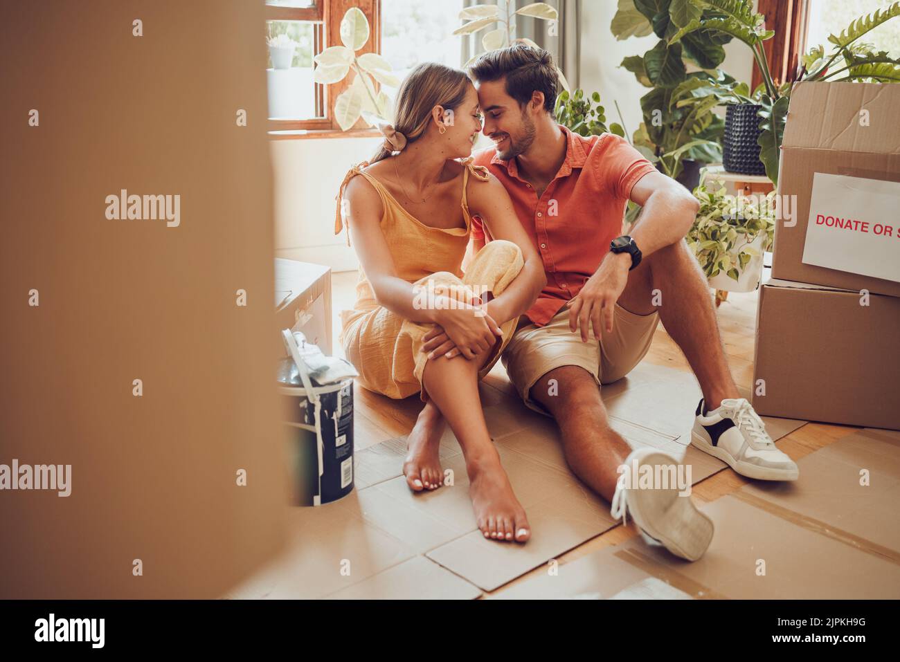 Romance, amusement et un moment intime entre un couple se déplaçant dans une nouvelle maison. Les jeunes amoureux sont affectueux, flirtant et appréciant une conversation Banque D'Images