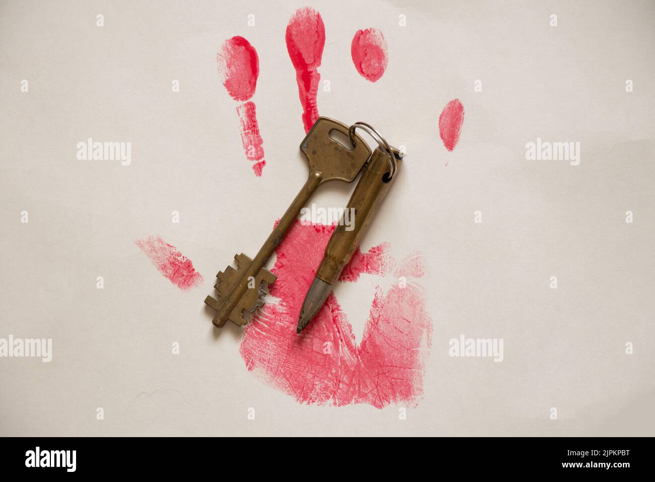 Imprimé à la main peint en rouge et balle avec clé de verrouillage de porte sur papier blanc gros plan, imprimé sanglant à la main et balle de mitrailleuse Banque D'Images