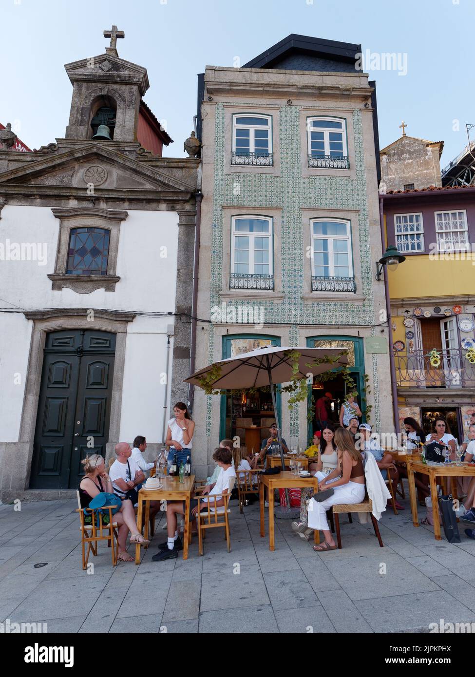 Les gens qui apprécient une soirée d'été à côté d'un restaurant, d'une église et de bâtiments de caractère dans le quartier Ribeira aka Riverside de Porto. Portugal. Banque D'Images