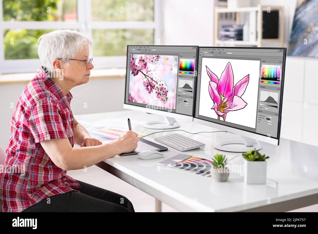 Web Graphic Designer travailler dans Office sur plusieurs écrans Banque D'Images