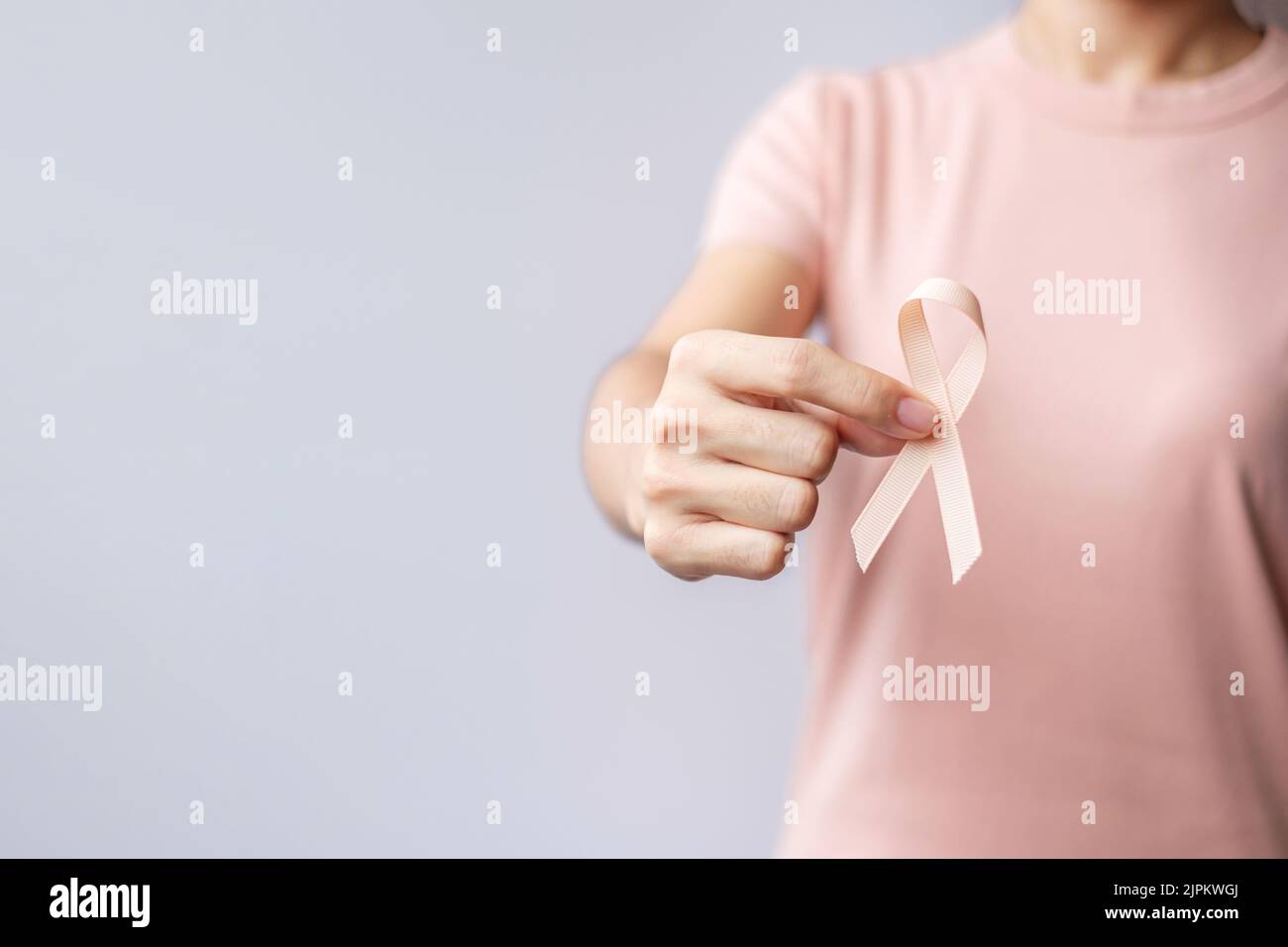 Femme tenant le ruban de pêche à la main pour le mois de septembre de sensibilisation au cancer utérin. Santé et concept de la Journée mondiale du cancer Banque D'Images
