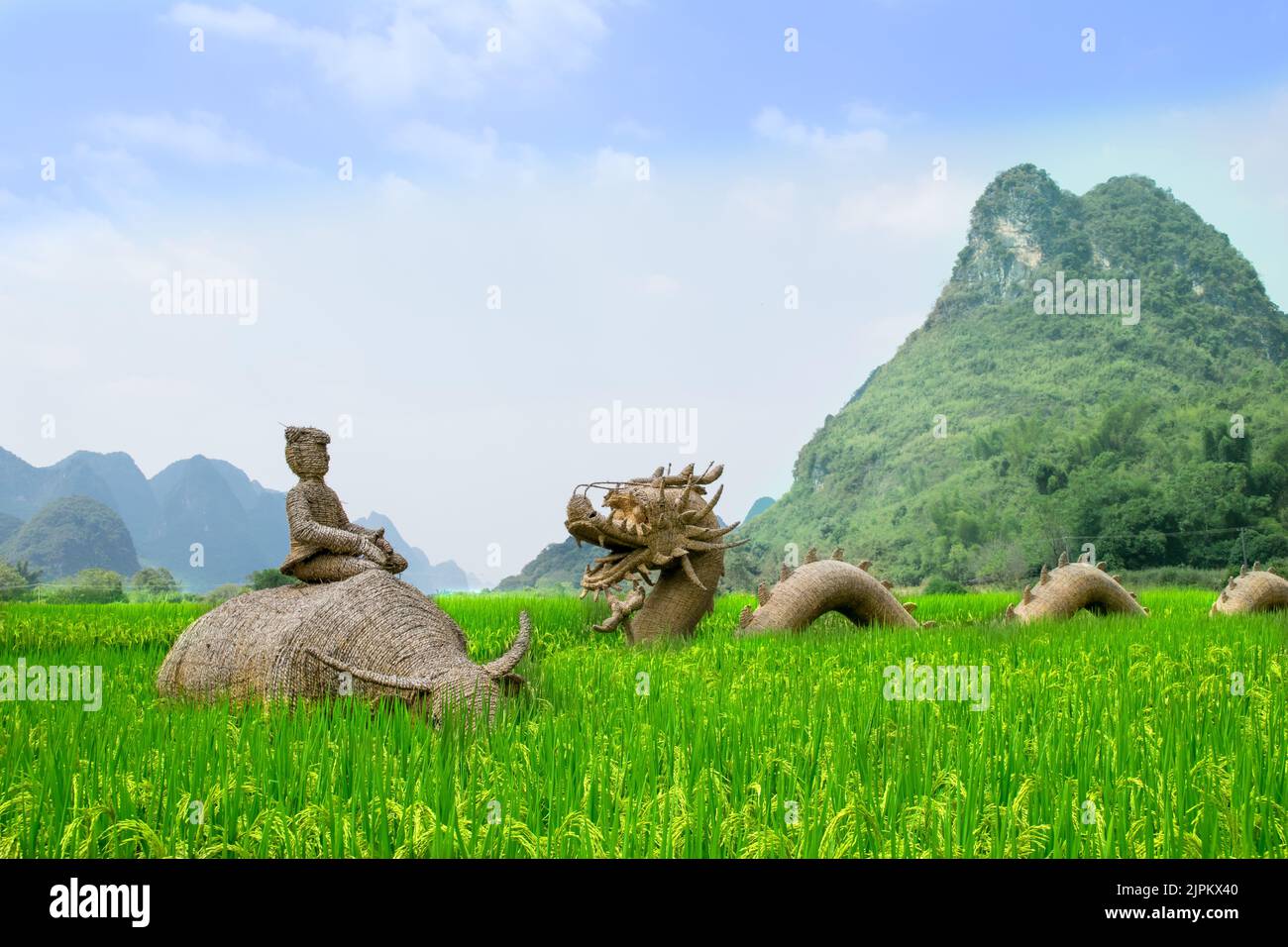 Sculptures en paille d'un dragon chinois et d'un fermier à cheval sur un Buffalo d'eau dans un champ de riz, dans le fond des montagnes Karst. Yangshuo, Chine. Banque D'Images