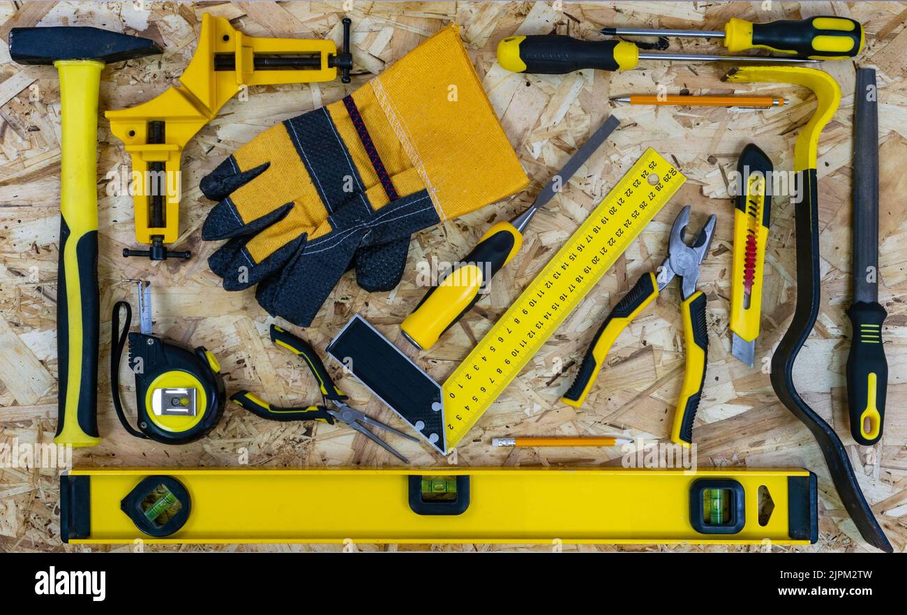 Outils de construction disposés sur un fond de plaque de construction osb. Tous les outils avec des éléments jaunes. Vue de dessus. Banque D'Images