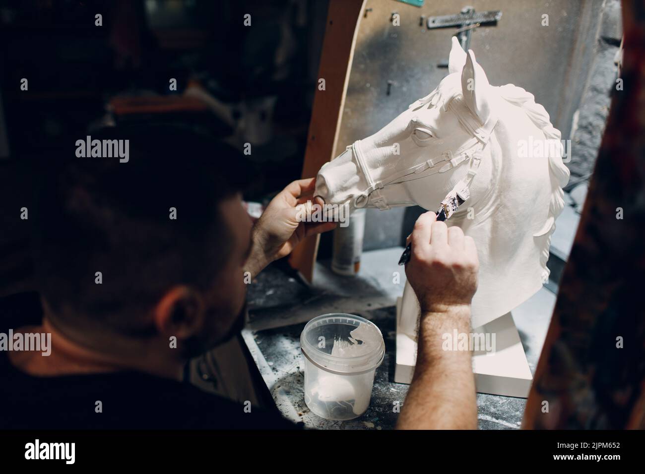 Un artisan crée un cheval à base de plâtre. Moule en gypse et masque en plastique sculptant et peignant Banque D'Images