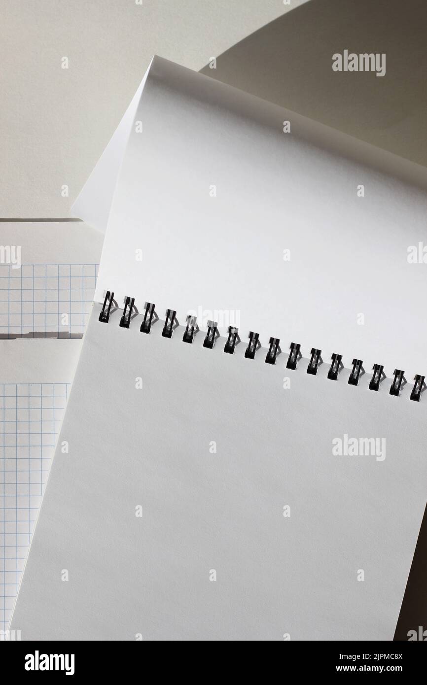 Modèle d'espace de copie métier. Mise à plat d'un espace de travail minimaliste avec bloc-notes spirale vierge sur fond blanc. Banque D'Images