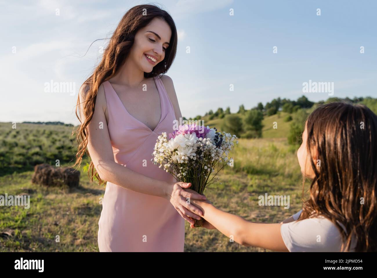 fille présentant des fleurs à la mère heureuse dans le pré le jour d'été Banque D'Images