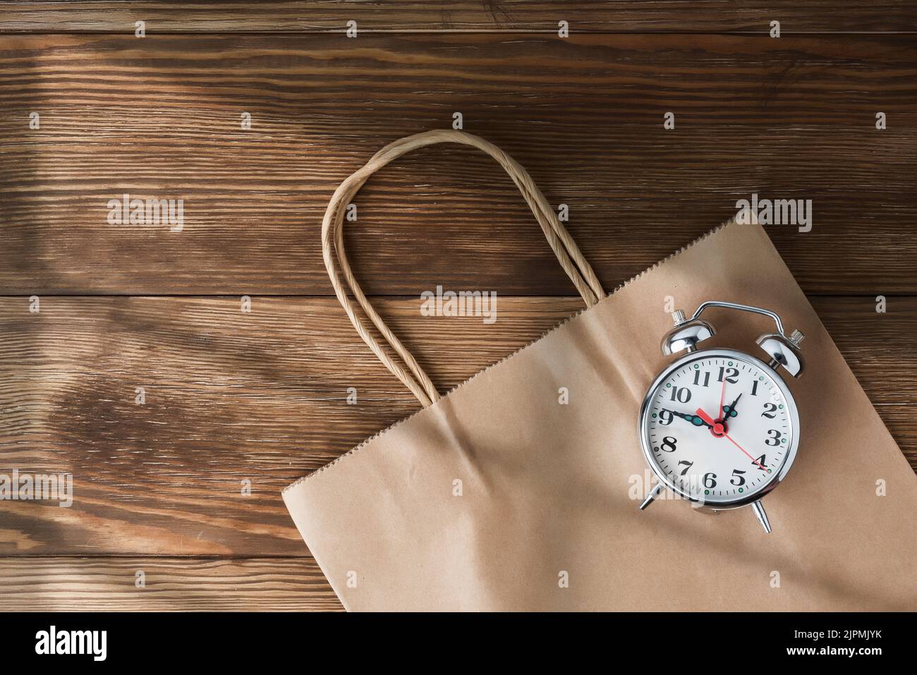 Il est temps de faire du shopping. Sac en carton avec horloge symbolisant l'arrivée des ventes. Rendez-vous au centre commercial et profitez des offres saisonnières Banque D'Images