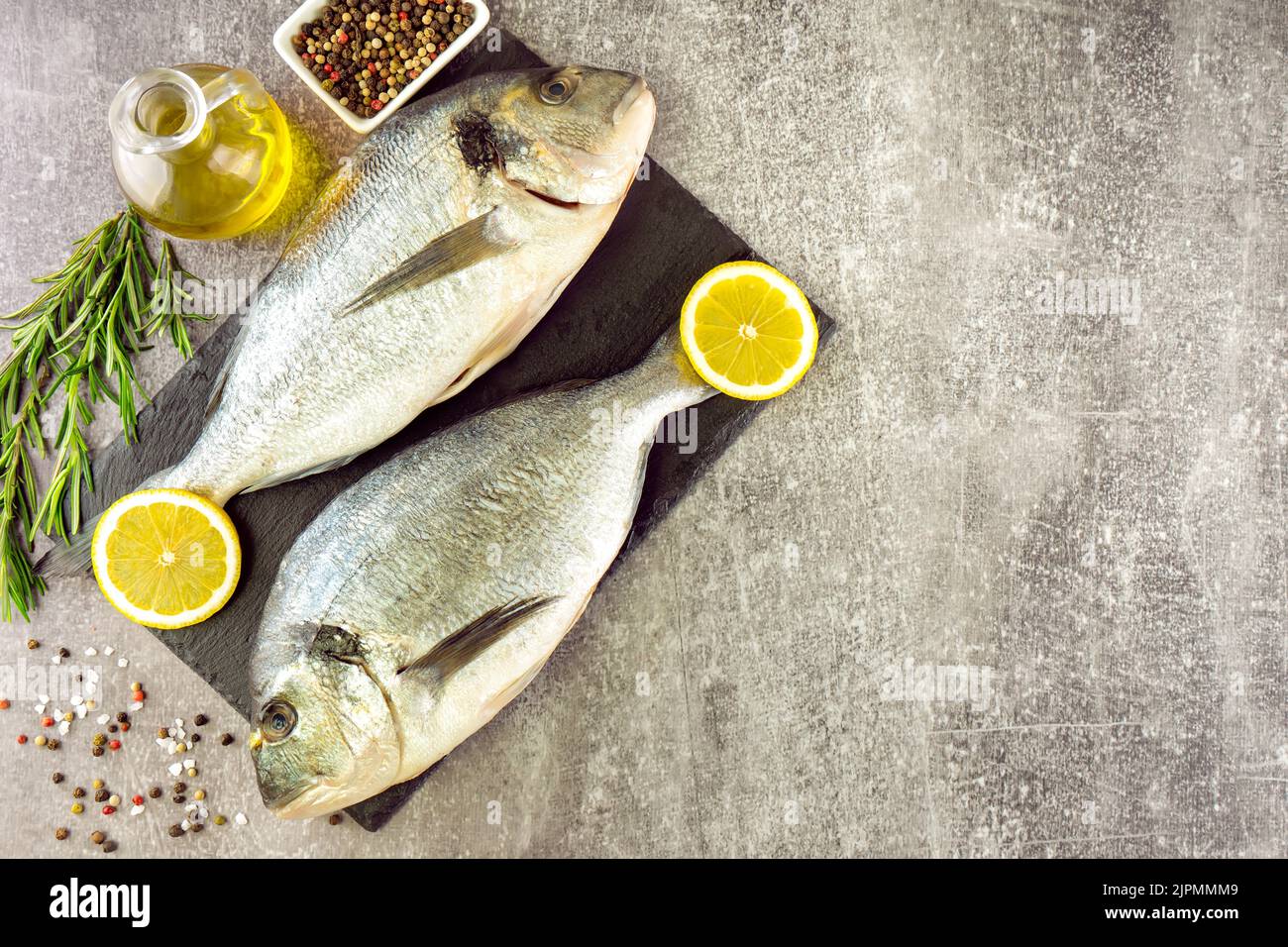 Poisson frais dorado et ingrédients pour la cuisine. Poisson cru dorada avec épices et herbes sur table en béton gris. Fruits de mer, restaurant, alimentation, nourriture saine b Banque D'Images