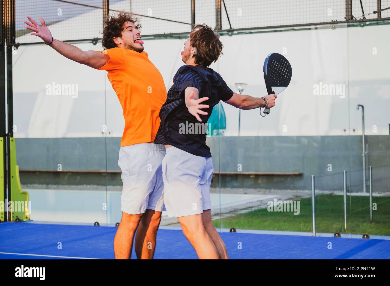 Portrait de deux sportifs souriants posant sur un terrain de padel en plein air avec des raquettes - les joueurs de padel embrassant après avoir gagné un match de padel Banque D'Images