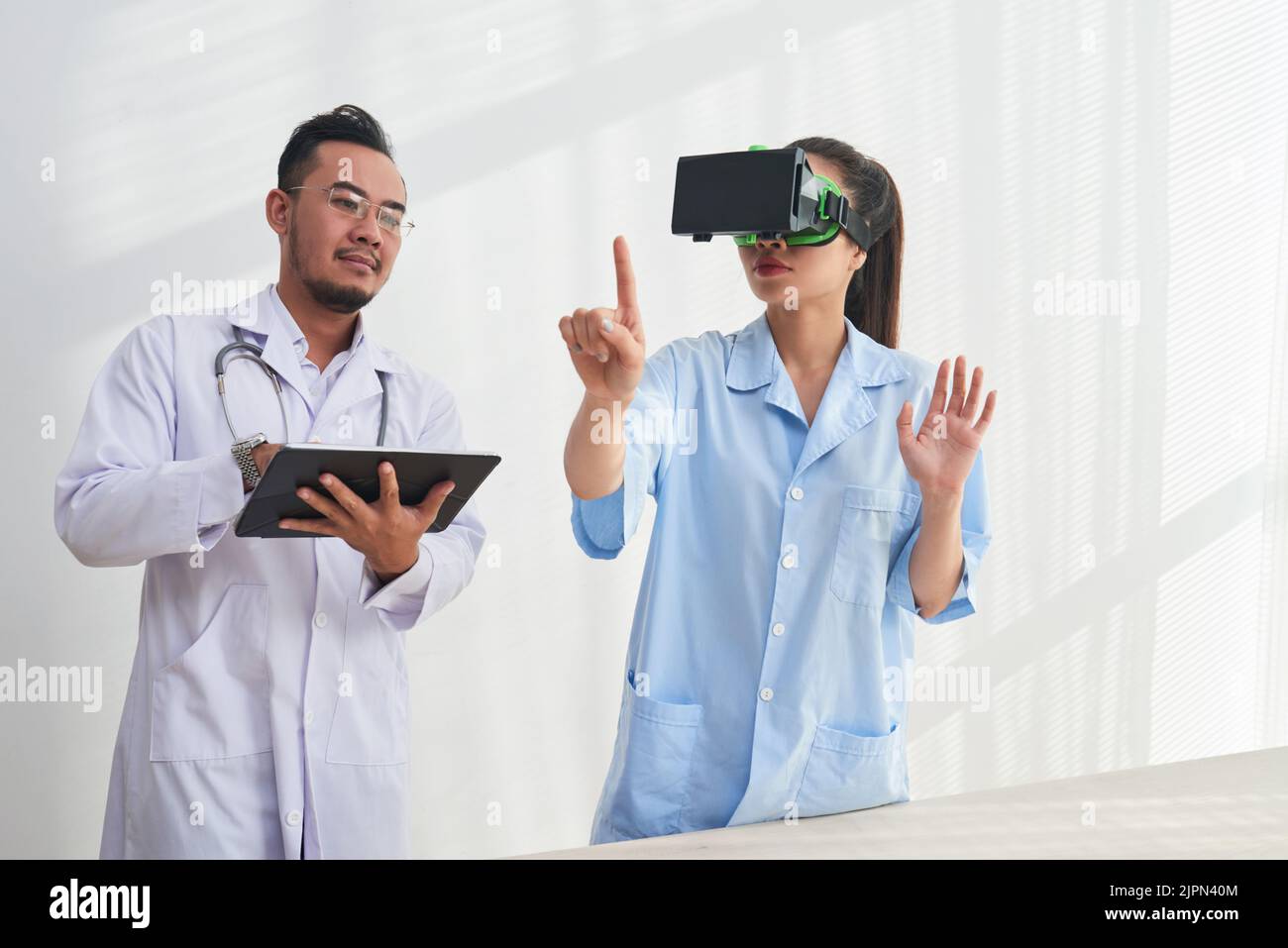 Une équipe talentueuse de médecins se sont réunis dans un laboratoire moderne et ont mené des expériences à l'aide d'une tablette numérique et d'un casque VR Banque D'Images