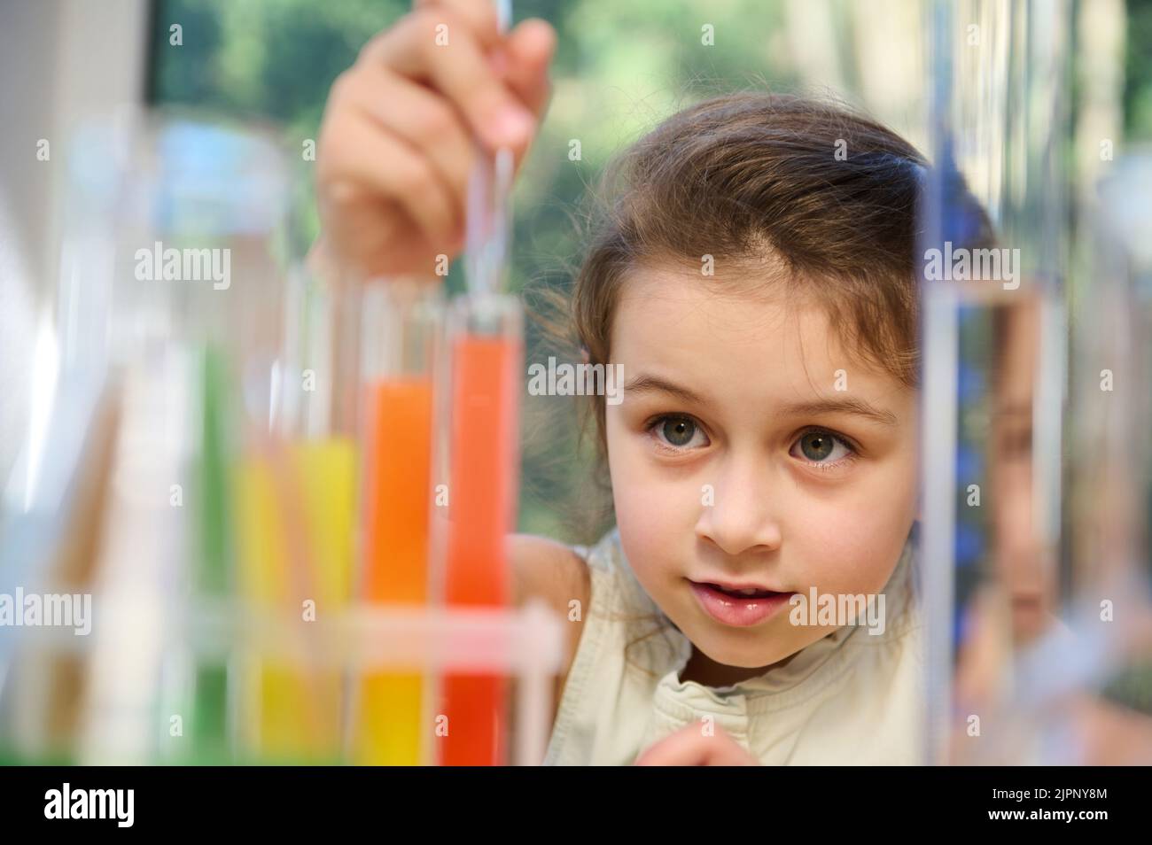 Une petite fille excitée utilisant un ensemble de chimie dans une salle de classe de sciences élémentaires. Une écolière fait des expériences chimiques scientifiques Banque D'Images