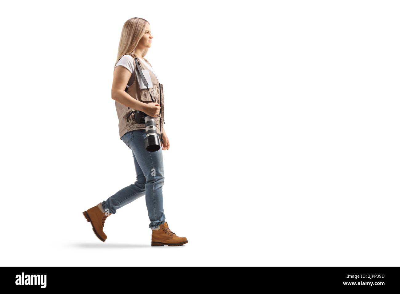 Prise de vue en profil d'une femme photographe marchant et portant un appareil photo professionnel isolé sur fond blanc Banque D'Images