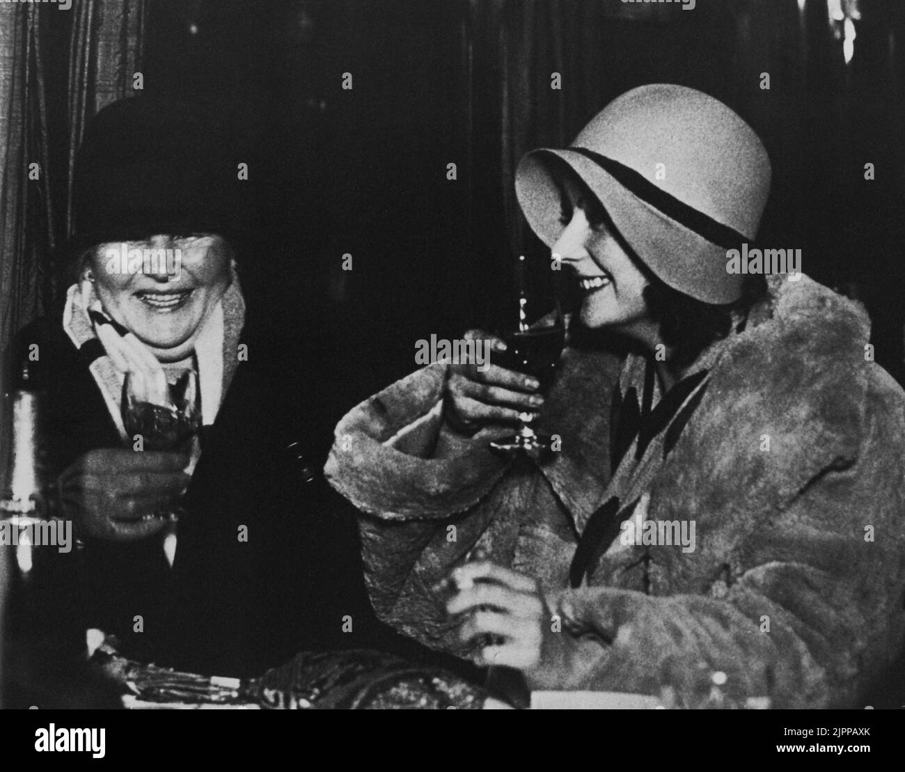 23 décembre 1928 , Stokholm , Suède : l'actrice GRETA GARBO ( 1905 - 1990 ) pour la première fois de retour en Suède de Hollywood après avoir obtenu la célébrité mondiale , dans cette boisson photo avec sa mère . Une des rares photos avec Greta rire en ce moment - FILM - CINÉMA - portrait - ritratto - sourire - sorriso - vino - vin - chapeau - cappello - cloche - pelliccia di cincilla - fourrure --- Archivio GBB Banque D'Images