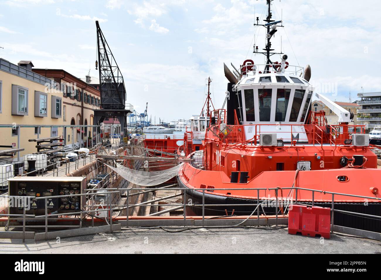 GÊNES, ITALIE - 14 AOÛT 2022 : un navire rouge dans un quai sec au chantier naval de Gênes, vu d'une zone piétonne publique. Banque D'Images
