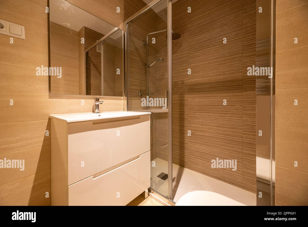 Salle de bains simple avec douche à l'italienne, miroir mural sans cadre, cabine de douche avec porte vitrée coulissante et armoire blanche avec tiroirs Banque D'Images