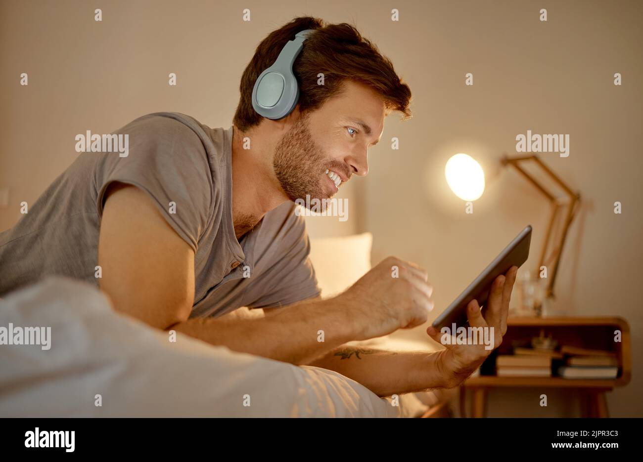 Casque, tablette numérique et lit pour regarder des films, des vidéos ou des séries en ligne la nuit dans la chambre. Homme sur des nouvelles de divertissement ou de film d'Internet Banque D'Images