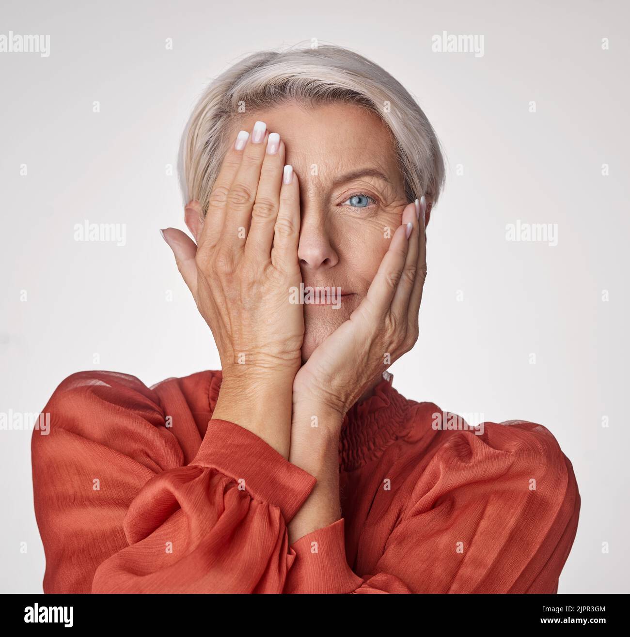 Beauté, santé et bien-être avec une femme âgée touchant son visage avec ses mains sur un fond de studio. Portrait d'une personne qui la couvre Banque D'Images