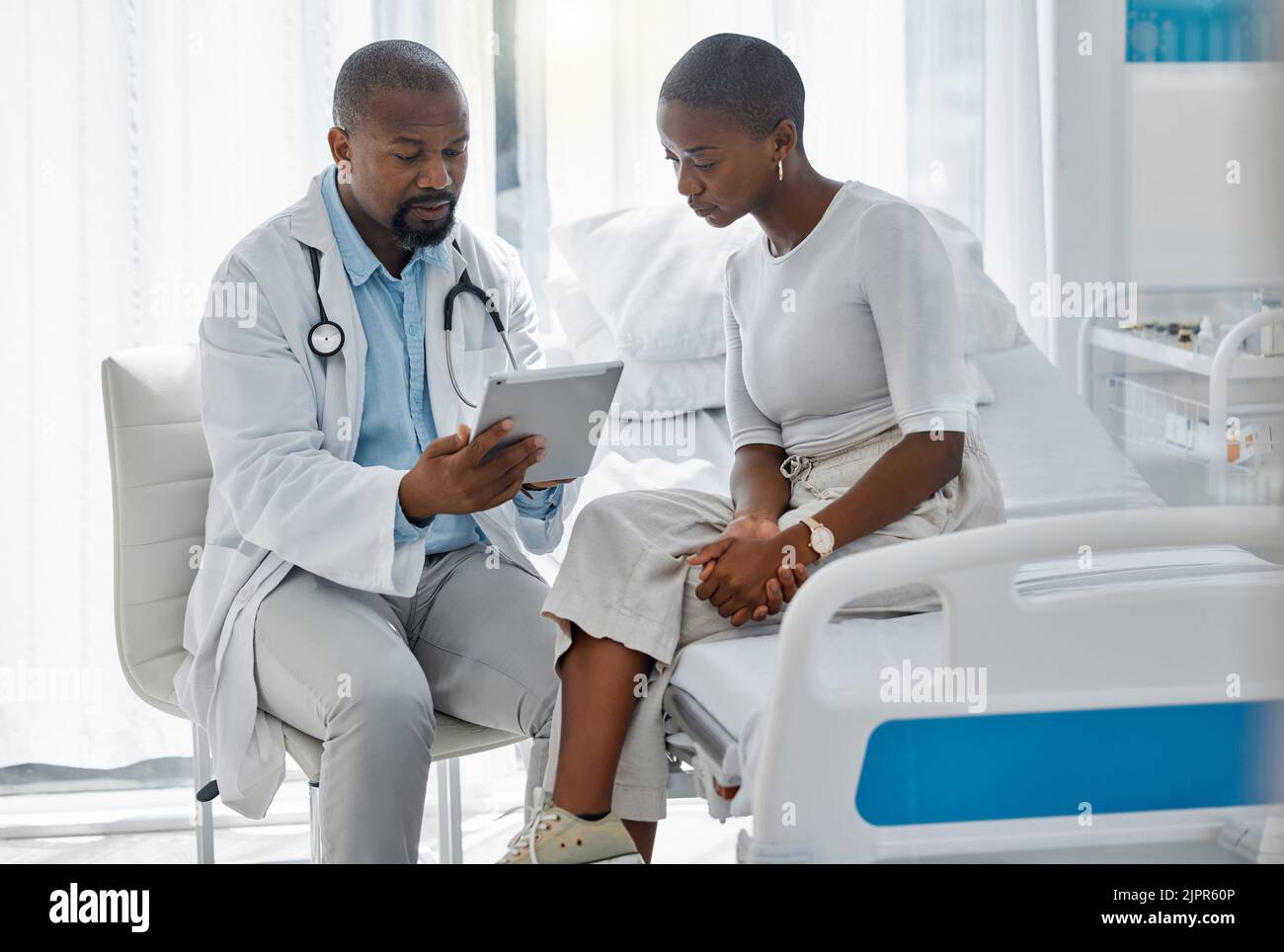 Médecin consultant un patient avec une tablette numérique, discutant du diagnostic et des examens médicaux à l'hôpital. Professionnel de la santé et médecin de confiance dans Banque D'Images