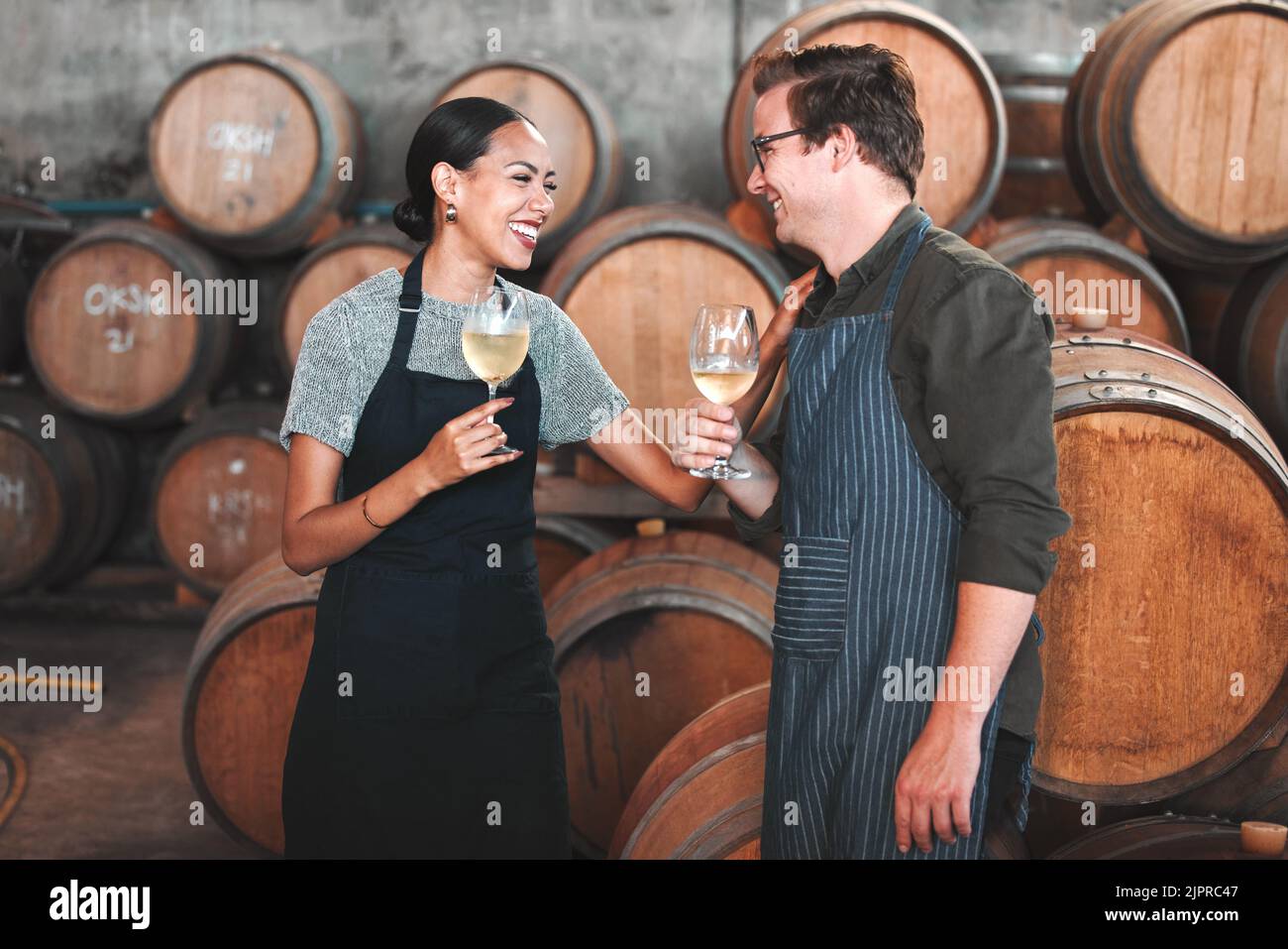 Viticulteur partenaires d'affaires s'amuser à parler à la cave de vinification, dégustation de vin blanc et rire. Jeune sommelier testant la saveur et le mélange de boissons alcoolisées Banque D'Images