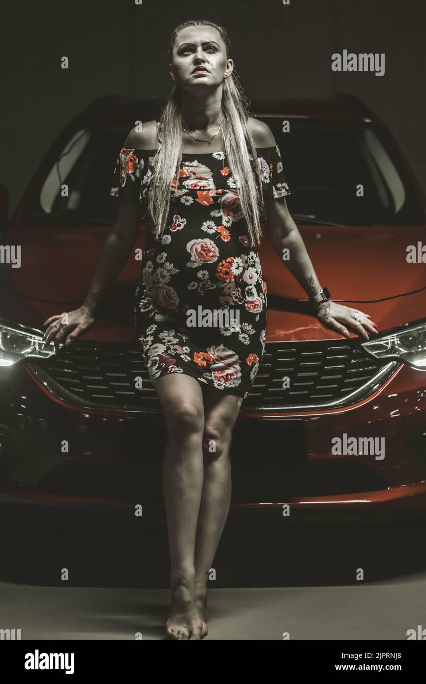 Belle dame se posant dans un garage sombre avec tipo de fiat rouge. Banque D'Images