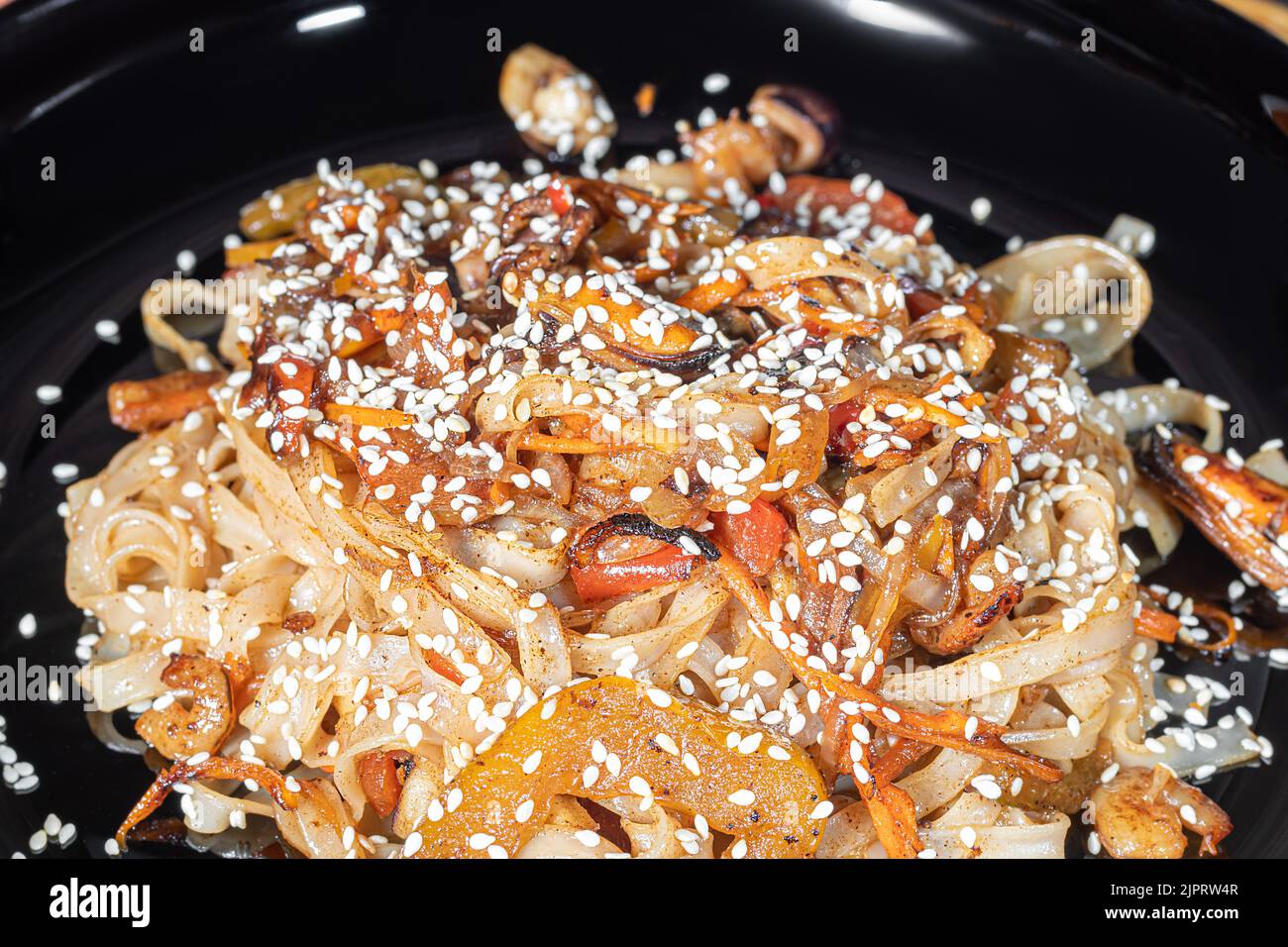 Nouilles Udon à la viande, aux champignons et aux légumes. Parsemé de graines de sésame. Cuisine asiatique, rôti sur fond noir, espace copie Banque D'Images