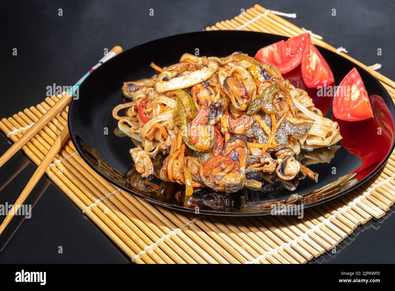 Nouilles Udon à la viande, aux champignons et aux légumes. Parsemé de graines de sésame. Cuisine asiatique, rôti sur fond noir, espace copie Banque D'Images