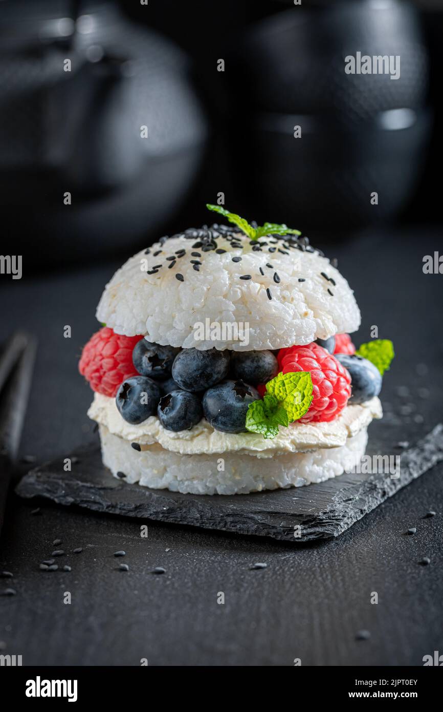 Hamburger à sushi sucré et aromatique aux baies et au mascarpone parsemé de graines. Dessert japonais à base de fruits et de riz. Banque D'Images