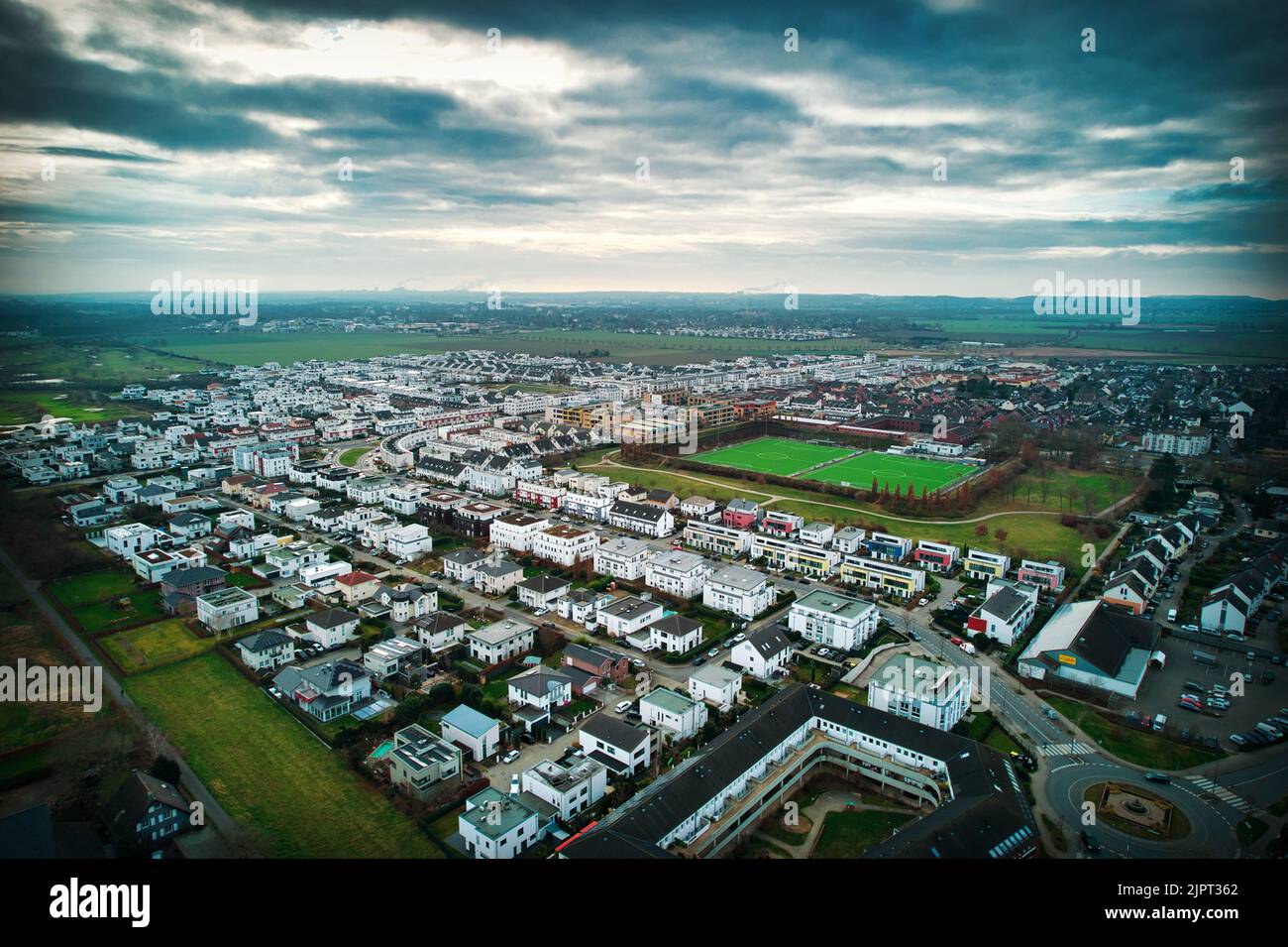 Photo aérienne d'une banlieue allemande avec des bâtiments similaires et un champ vert par jour nuageux Banque D'Images