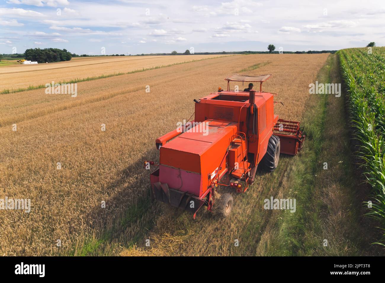 Concept de travail à col bleu. Fier opérateur de moissonneuse-batteuse utilisant sa moissonneuse-batteuse rouge pour récolter son champ. Perspective de drone. Photo de haute qualité Banque D'Images