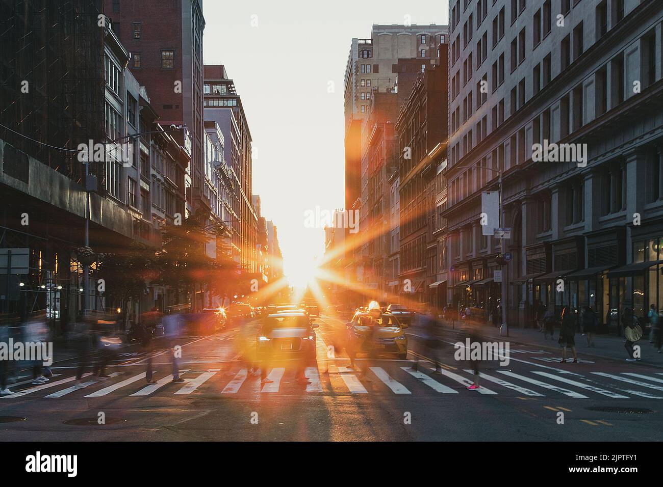 Les gens qui traversent un passage en croix à l'intersection animée de 5th Avenue et 23rd Street à New York City avec la lumière du coucher du soleil qui brille en arrière-plan Banque D'Images