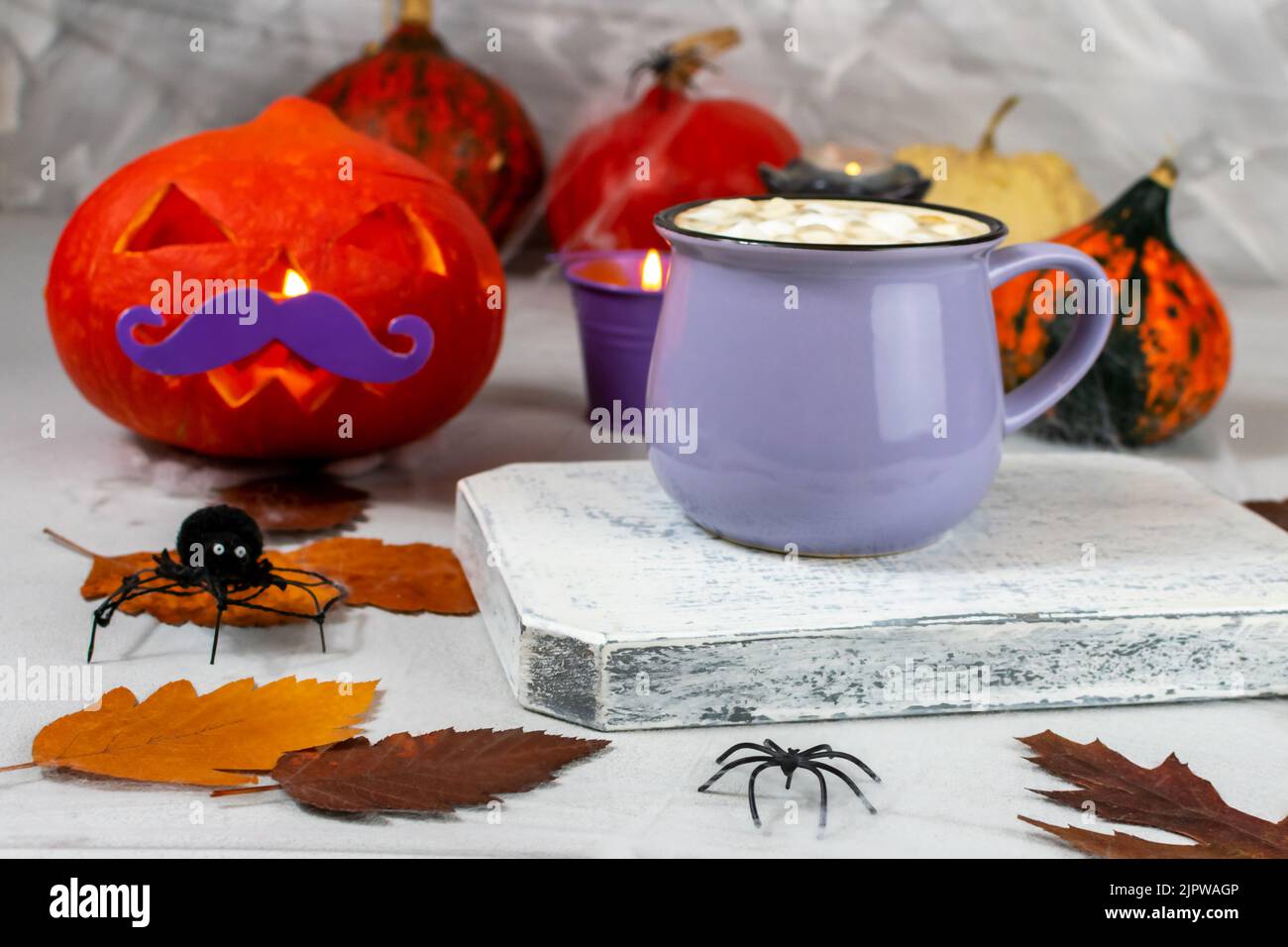 Citrouille pour Halloween avec une tasse de café et des biscuits sur le fond d'un mur avec des fantômes, des chauves-souris, des araignées, des bougies, des citrouilles, feuilles. Sélectif Banque D'Images