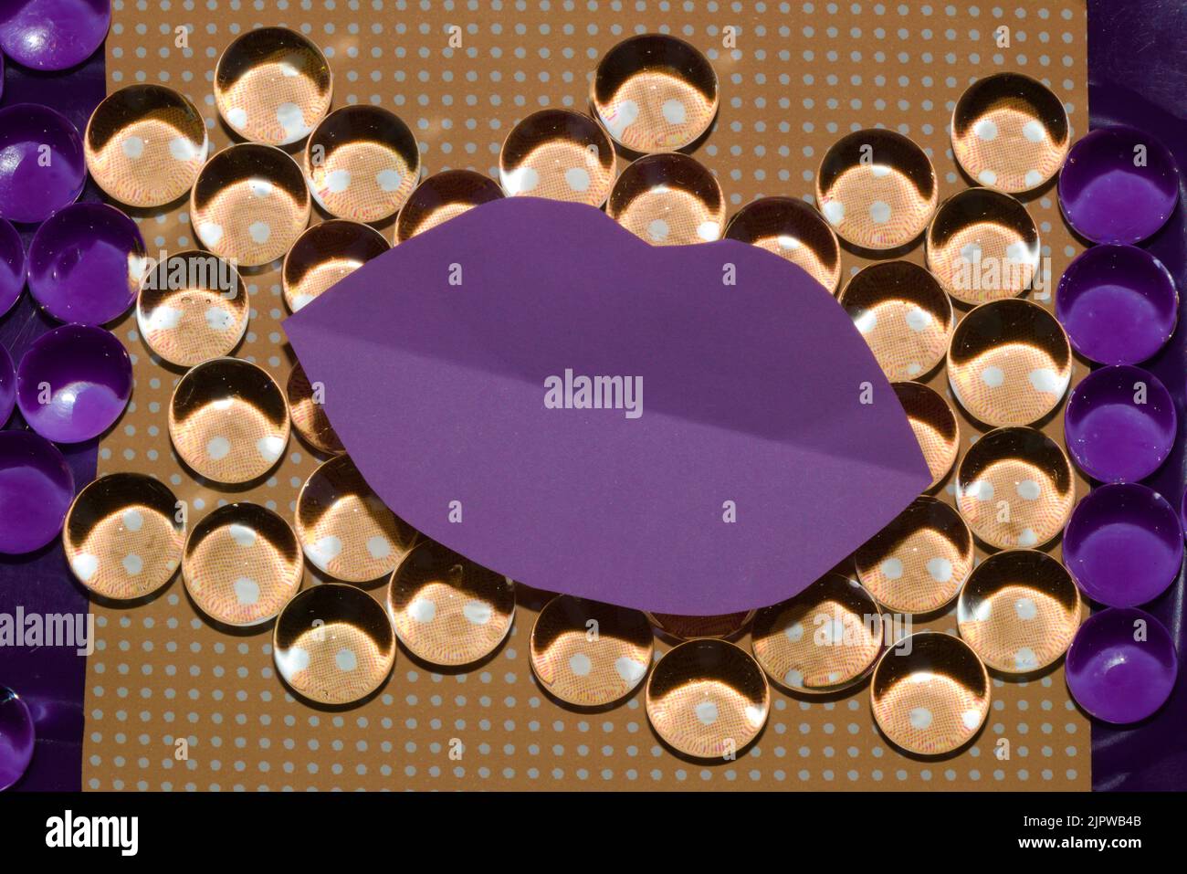 Arrière-plan orange abstrait avec des points et des lèvres de papier violet comme espace de copie et des perles qui reflètent les couleurs différemment des deux côtés partie violette, été a Banque D'Images