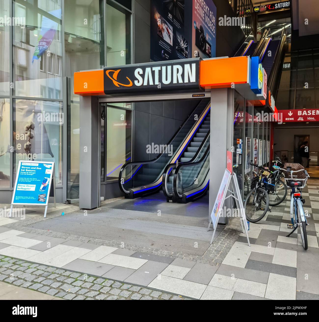 Une entrée d'une succursale du magasin électronique Saturn avec un escalier roulant dans le centre-ville de Kiel, Allemagne Banque D'Images
