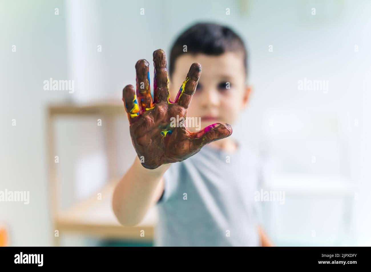 Jeune garçon montrant sa paume colorée peinte avec des peintures lavables et non toxiques après un jeu d'art à l'école maternelle. Peinture de doigt pour les enfants compétences sensorielles, la créativité et le développement de l'imagination. Photo de haute qualité Banque D'Images