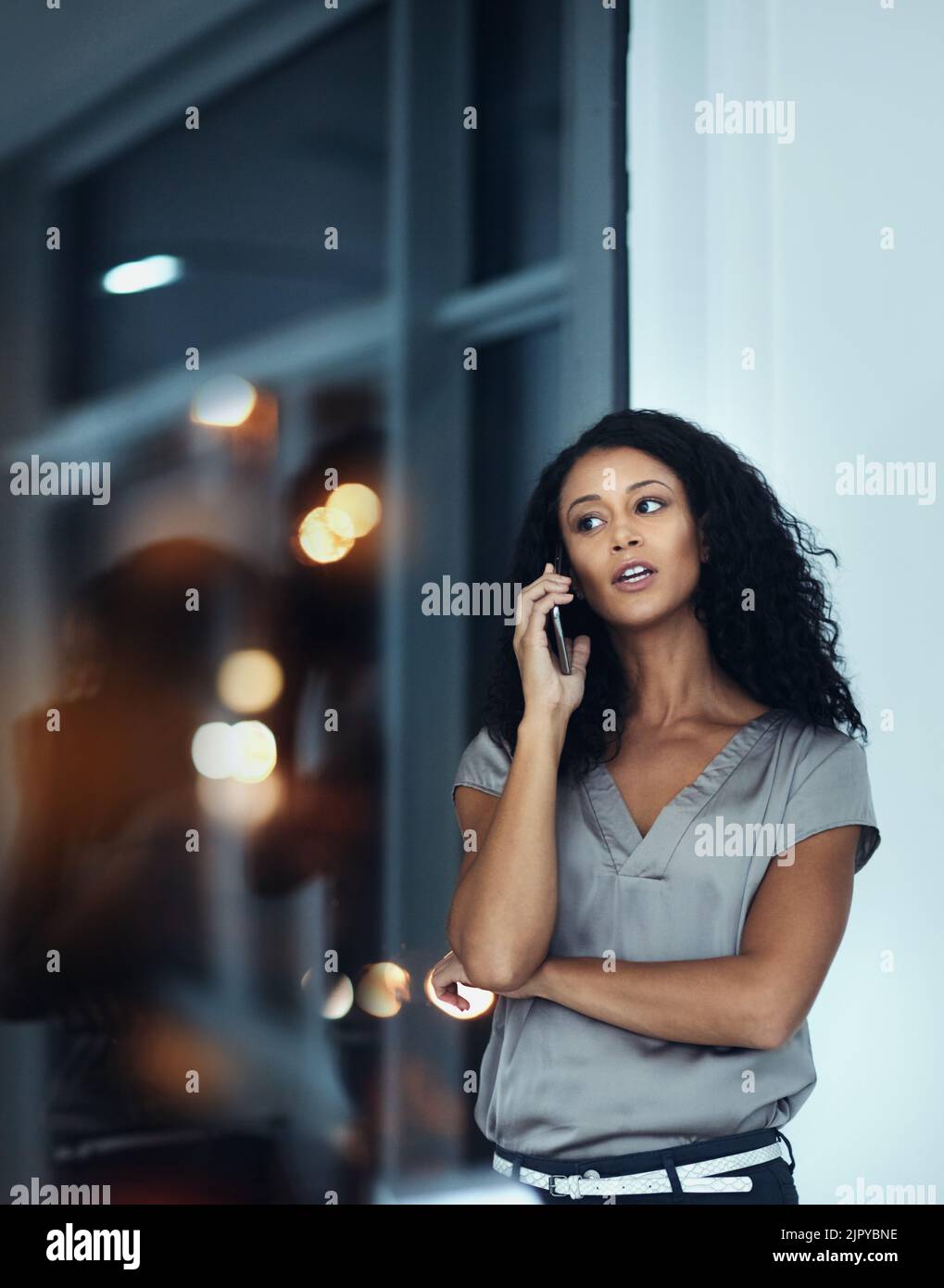 Il vous suffit de vous faire savoir que la messagerie instantanée est toujours au bureau. Une jeune femme d'affaires parle sur un téléphone portable tard dans la nuit au travail. Banque D'Images