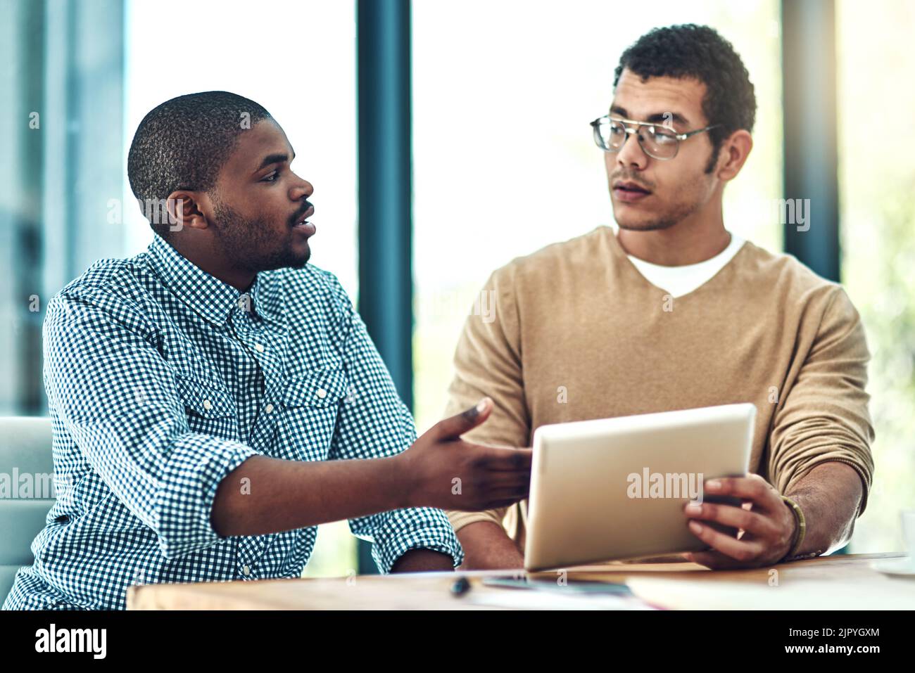 Cet outil nous fait gagner du temps. Deux jeunes concepteurs discutent de quelque chose sur une tablette numérique. Banque D'Images