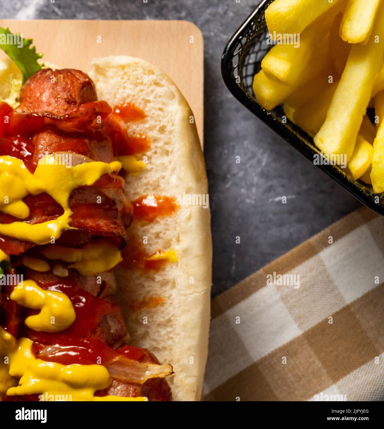 Un sandwich hot dog avec de la moutarde, du catap et des légumes frais, ainsi qu'un panier de frites Banque D'Images