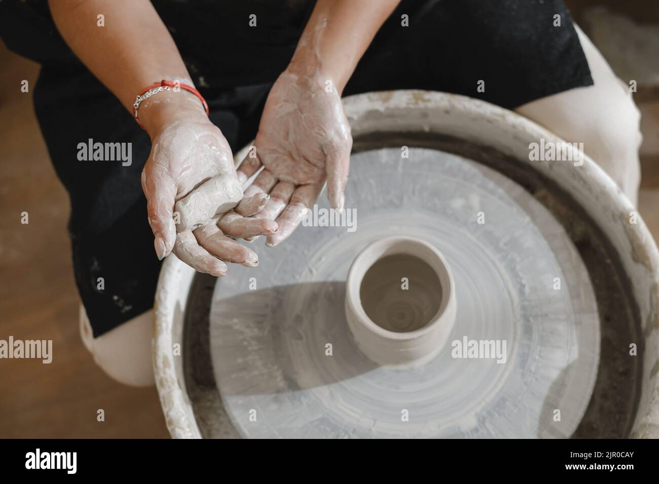 Potier mains au-dessus de la roue. Artiste de poterie indépendant dans le studio créatif modélisation à partir d'argile brute façonnant la tasse ou le pot fait à la main. Production de céramique Banque D'Images