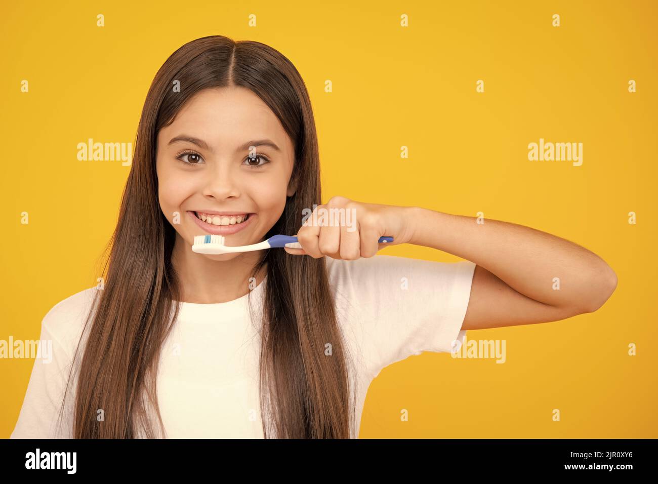 Joyeux portrait d'adolescent. Une adolescente se brossant les dents sur un fond jaune isolé. Brosse à dents d'hygiène quotidienne pour adolescents, routine du matin Banque D'Images