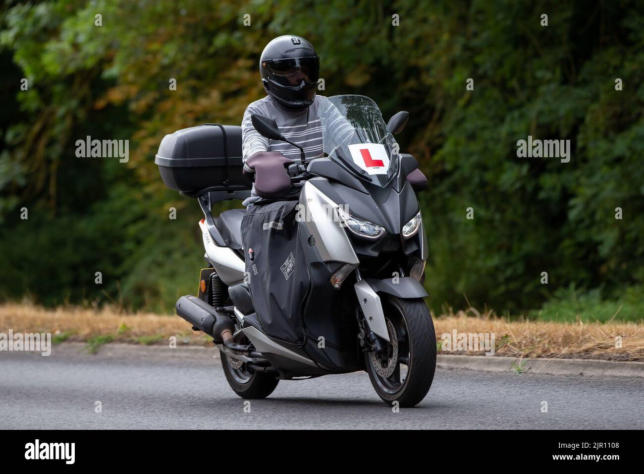 Apprenant avec L plaques à conduire une moto Yamaha argentée Banque D'Images