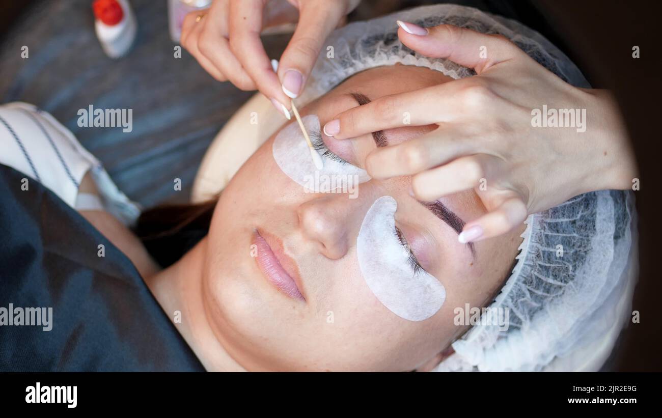 salon de beauté. gros plan, procédure d'extension des cils. le maître essuie les cils au client avec un coton-tige imbibé d'antiseptique, prépare le client pour la procédure. Photo de haute qualité Banque D'Images