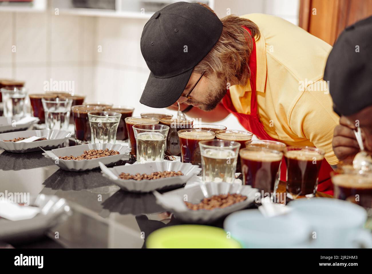 Un employé de sexe masculin goûtant du café et sentant l'arôme de nombreuses tasses Banque D'Images