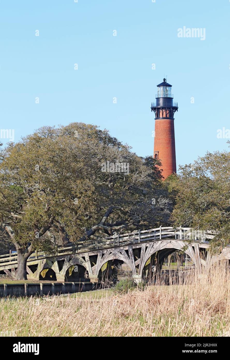 La structure en briques rouges du phare de Currituck Beach s'élève sur un pont en bois au-dessus d'une partie du détroit près de Corolla, en Caroline du Nord Banque D'Images