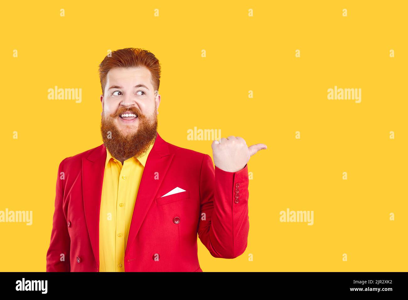 Drôle d'homme caucasien avec la barbe et la moustache montrant le doigt à l'espace de copie se dresse sur jaune studio Banque D'Images