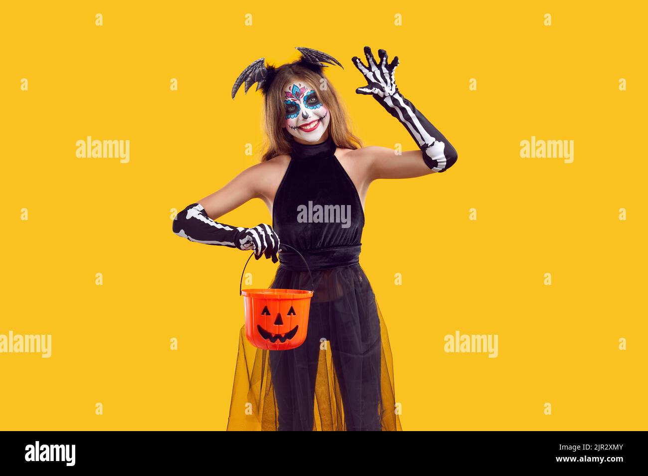 Un enfant heureux en costume d'Halloween effrayant tenant un panier de friandises, en signe de bonjour et de sourire Banque D'Images